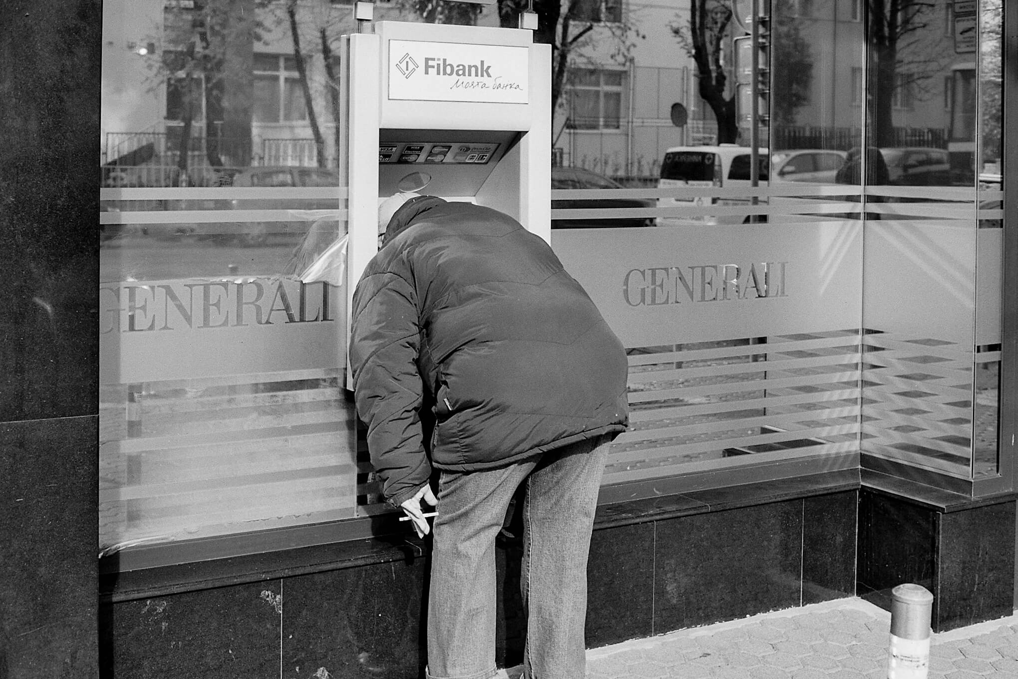 Black and white photo of a man using an ATM 